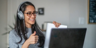 Woman with headset smiling from behind a computer screen